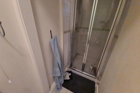 A compact bathroom featuring a shower enclosure...