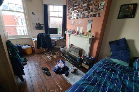 A cozy single bedroom featuring a large window ...