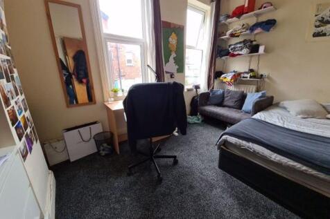 A cozy bedroom featuring a bed, desk, and shelv...