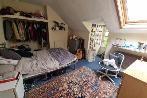 A cozy bedroom with a sloped ceiling and a skyl...