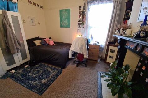 A cozy bedroom featuring a bed, desk, and a win...