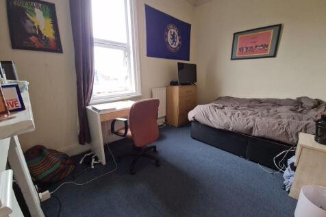 A cozy single bedroom featuring a bed, a window...