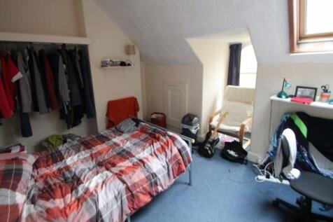 A cozy bedroom featuring a single bed with a co...