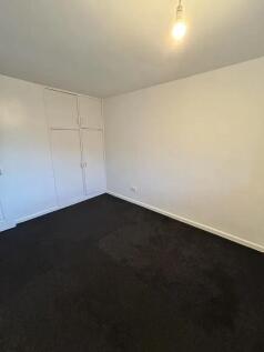 A simple double bedroom featuring clean white w...