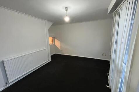 A simple and clean single bedroom with white wa...