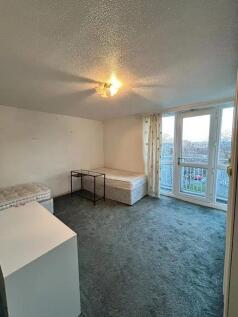 A modest room featuring a single bed, a small d...