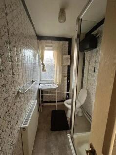 A compact bathroom featuring a shower enclosure...