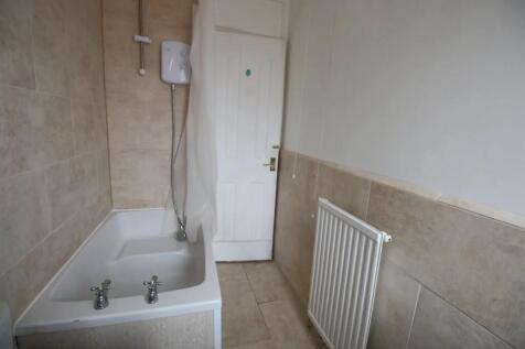 A neat bathroom suite featuring a white bathtub...