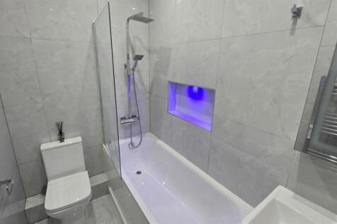 A modern, clean bathroom featuring a bathtub wi...