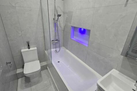 A modern and clean bathroom featuring a bathtub...