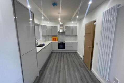 A modern, well-lit kitchen with sleek white cab...