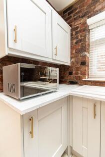 Bright, modern kitchen corner with white cabine...