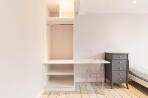 Bright, neutral bedroom corner with built-in sh...