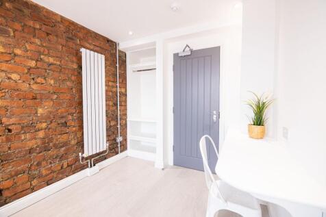 Bright, modern single bedroom with exposed bric...