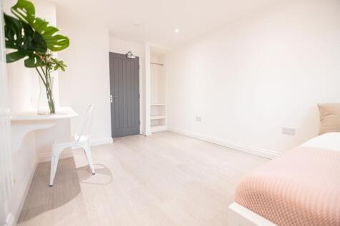 Bright, modern bedroom with pale wood flooring,...