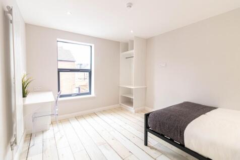 Bright, modern double bedroom with pale wooden ...