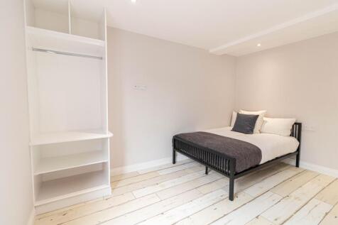 Bright, minimalist bedroom with a neatly made d...