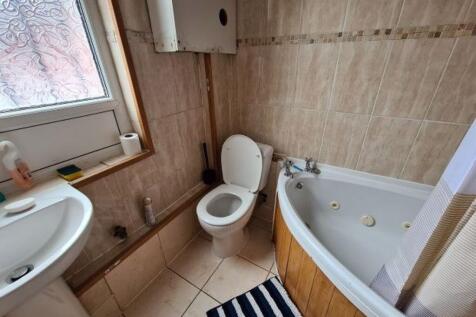 A bright bathroom suite featuring a corner bath...