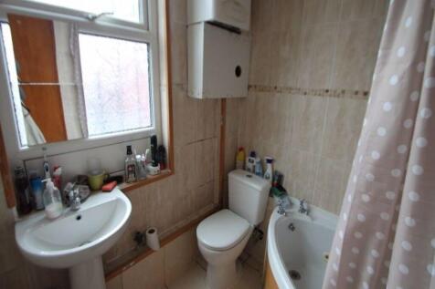 A compact bathroom featuring a corner bathtub w...