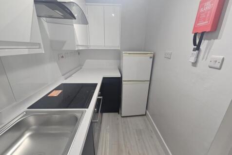 A modern, clean kitchen featuring white cabinet...