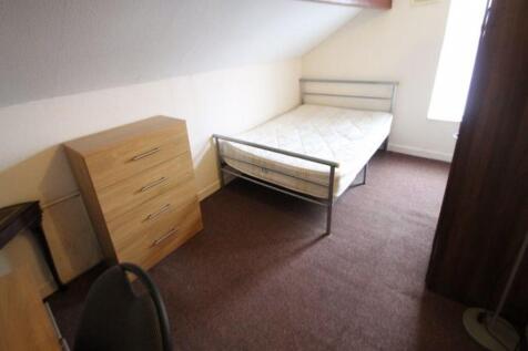 A cozy single bedroom featuring a simple bed fr...