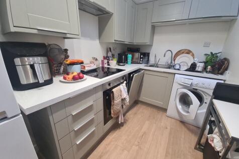 Modern U-shaped kitchen with pale cabinetry, in...