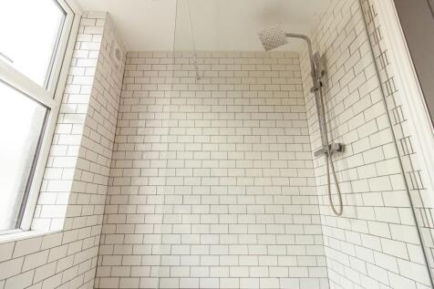 Bright, modern shower area with white subway ti...
