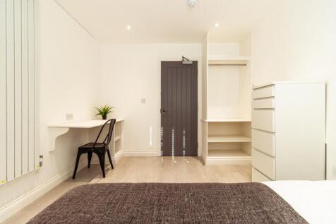 Bright, modern bedroom with built-in shelving a...