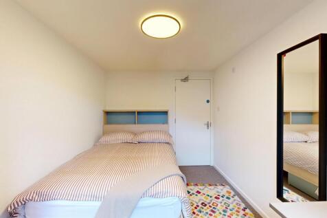 Neat, simply furnished bedroom with a bed, neut...