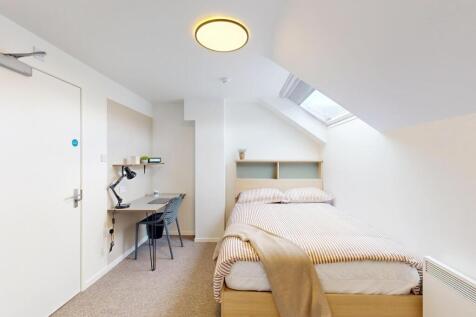 Bright, neatly arranged single bedroom with a c...