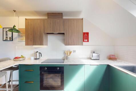 Bright, modern kitchen with green lower cabinet...