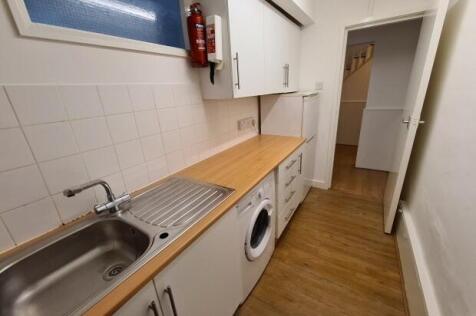 Long galley-style kitchen with wooden counterto...