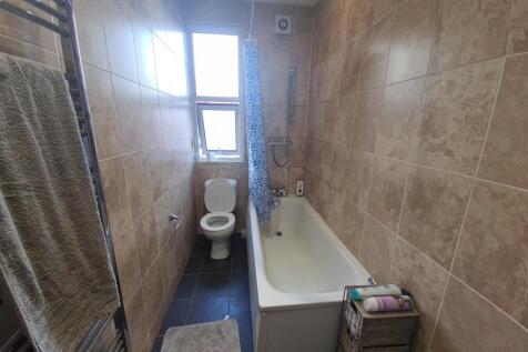 A clean bathroom featuring a bathtub, a toilet,...