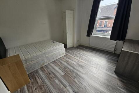 A modest single bedroom featuring a simple bed ...