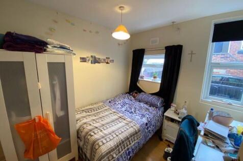 Cozy single bedroom featuring a neatly made bed...