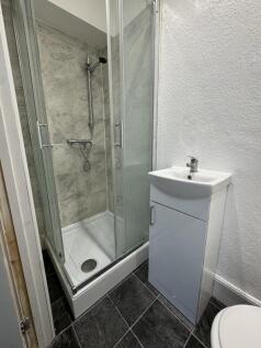 A modern bathroom featuring a clean glass-enclo...