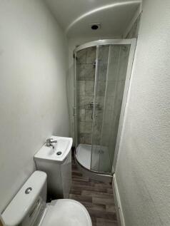 Compact bathroom featuring a modern corner show...