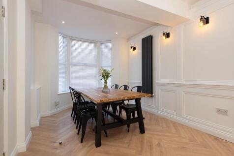 Bright, stylish dining area with a large wooden...