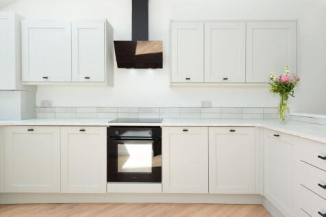 Bright modern kitchen with white cabinetry, int...