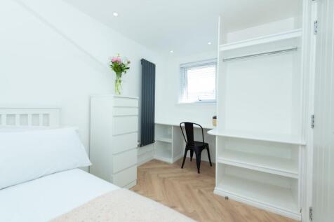 Bright, modern bedroom with pale wood herringbo...