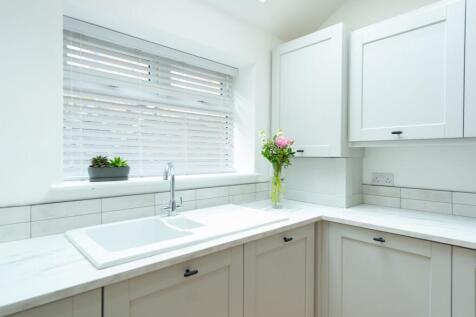 Bright, modern kitchen with a white sink set in...