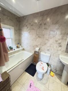 A clean and well-lit bathroom featuring a batht...