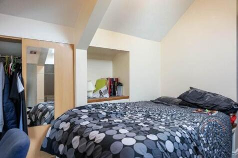 A cozy bedroom featuring a bed with a patterned...