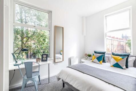 A bright, well-lit bedroom featuring a comforta...