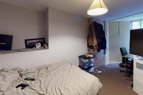 A cozy bedroom with a neatly made bed, a window...