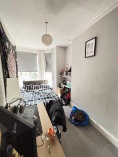 A cozy student&#39;s bedroom featuring a bed near t...