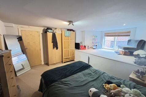 A well-lit bedroom featuring a comfortable doub...