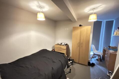 A cozy bedroom featuring a single bed with a da...