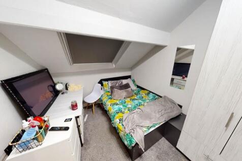 A cozy single bedroom featuring a neatly made b...