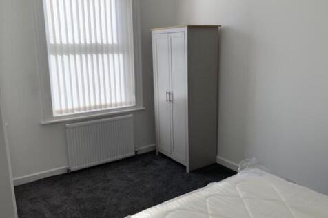 A tidy student bedroom featuring a bed, a wardr...